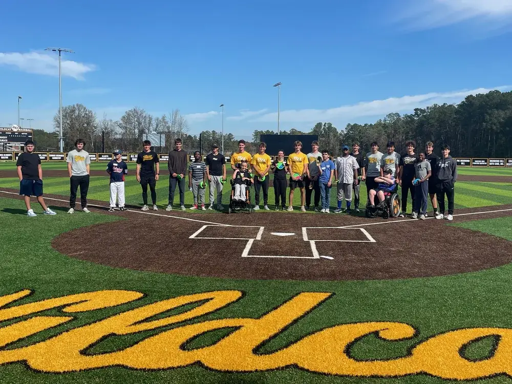 Campers and Richmond Hill High School baseball players line up at home plate at Wildcat Park during the Adaptive Baseball Camp